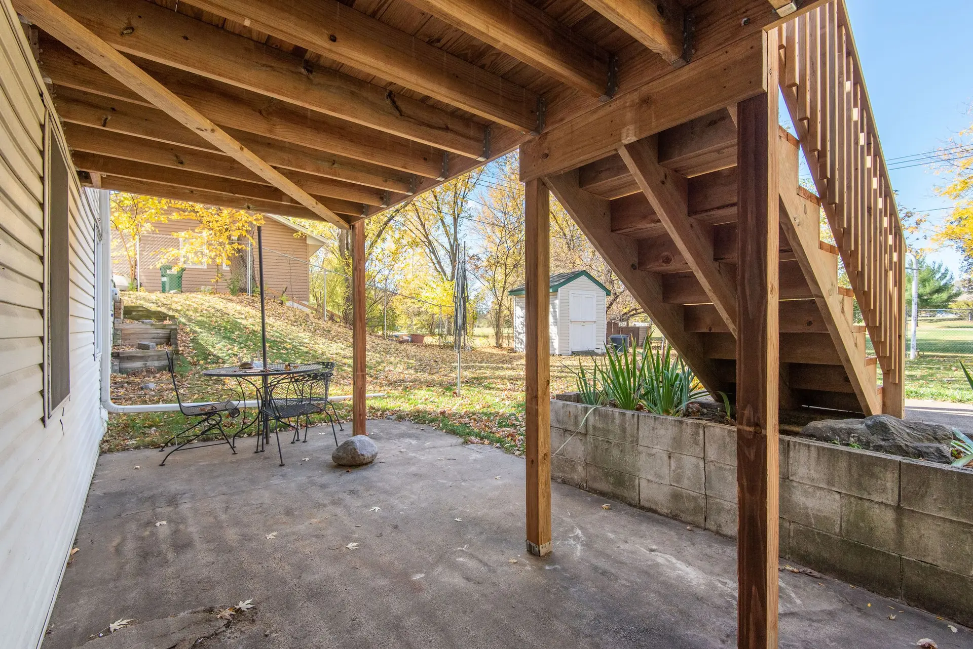 Raised wood deck on posts with a stair down to a concrete patio