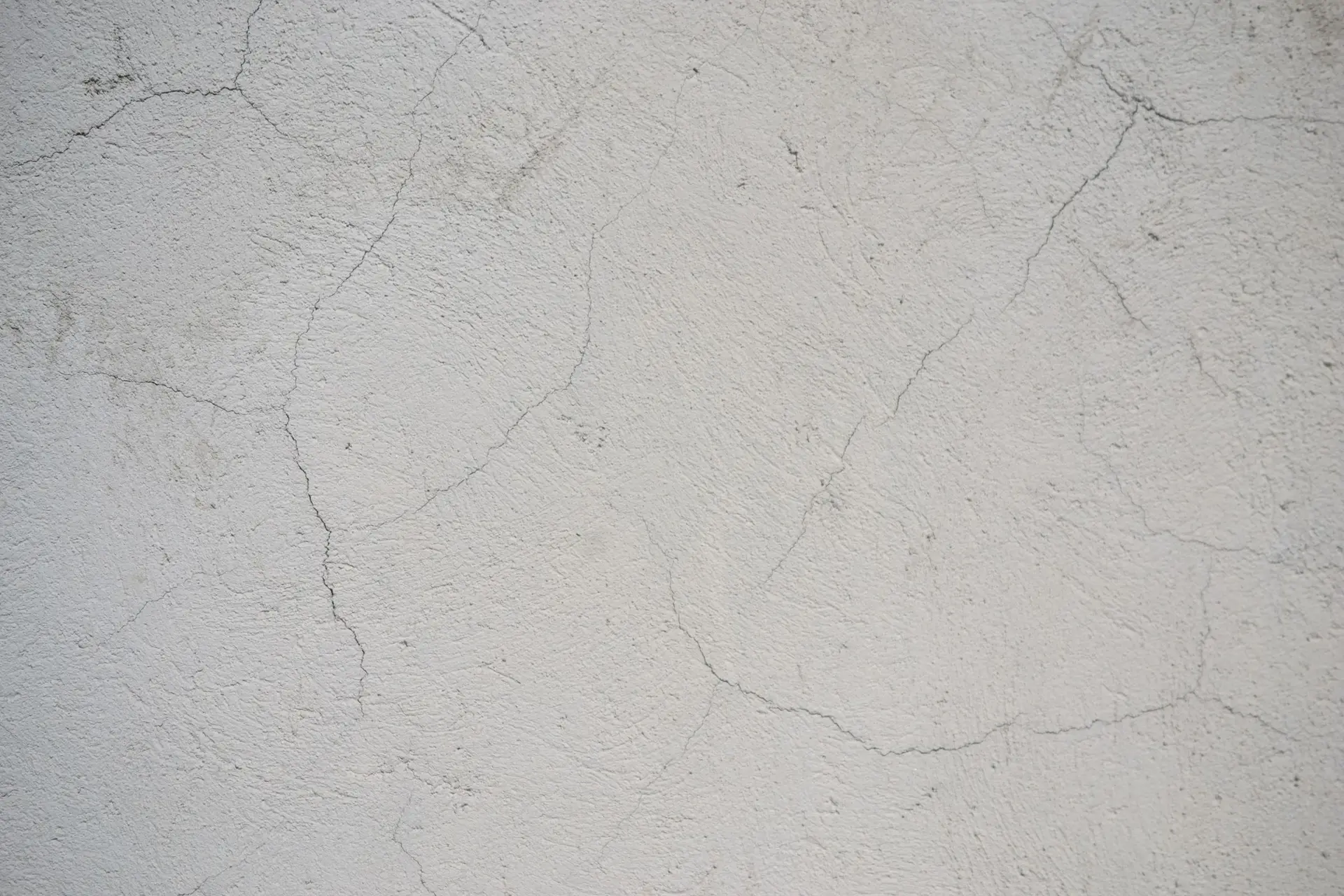 Cracked white plaster wall surface