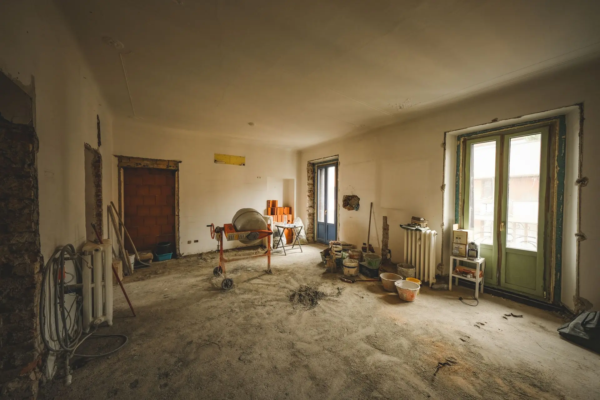 Room stripped for renovation with a cement mixer and tools on the floor